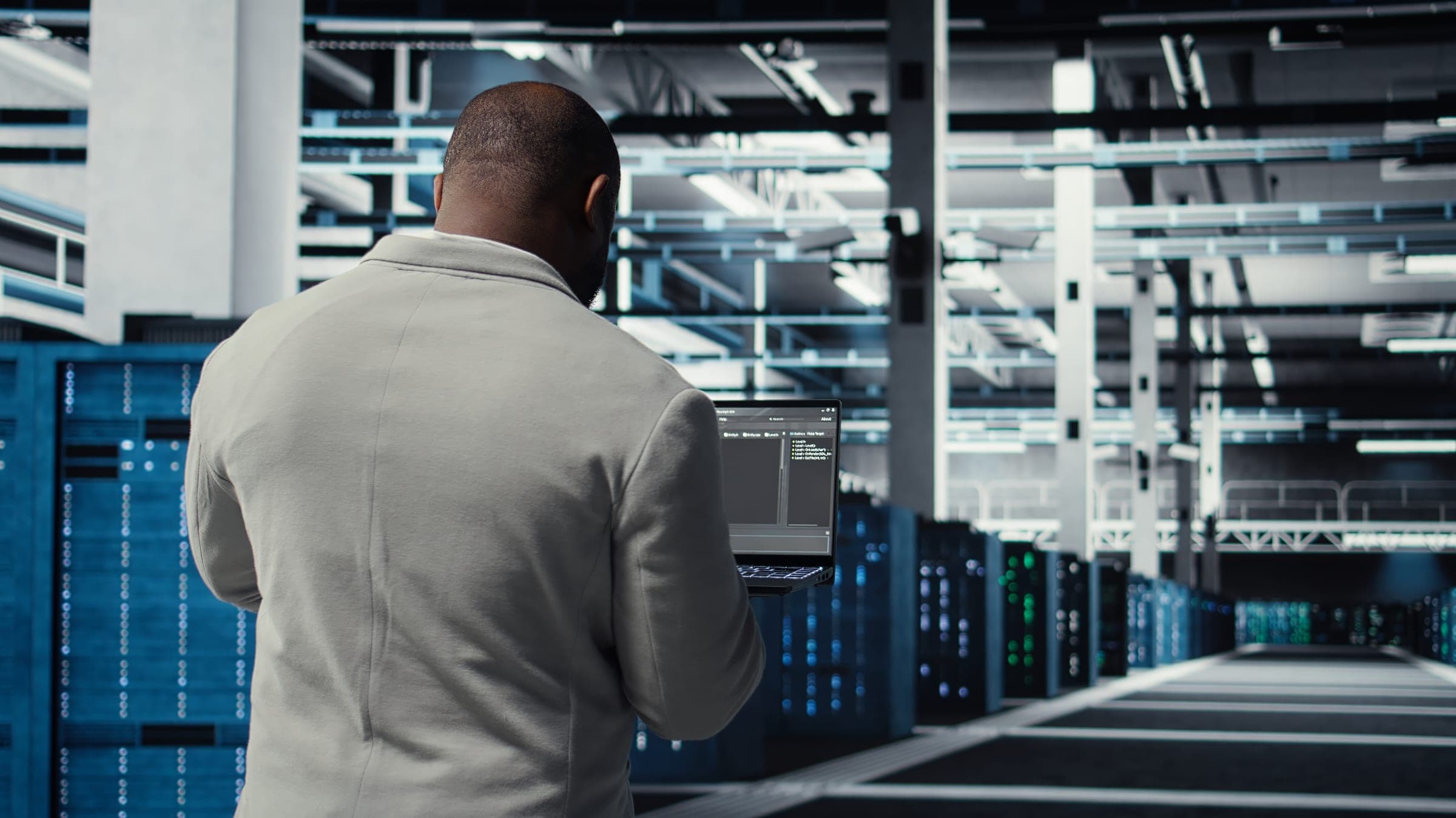 Technician using a laptop between rows of data-center racks.